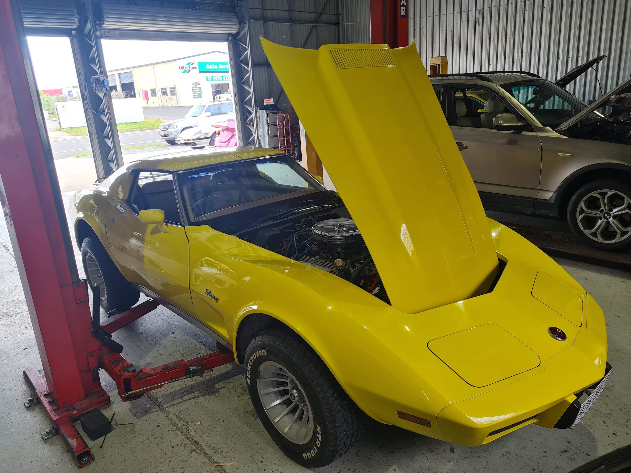 Yellow Chevrolet Corvette Stingray with the bonnet up on the workshop floor
