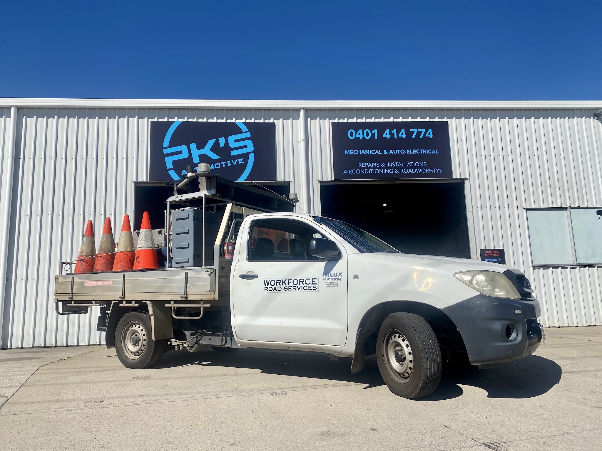 A work ute parked at the roller doors of the workshop